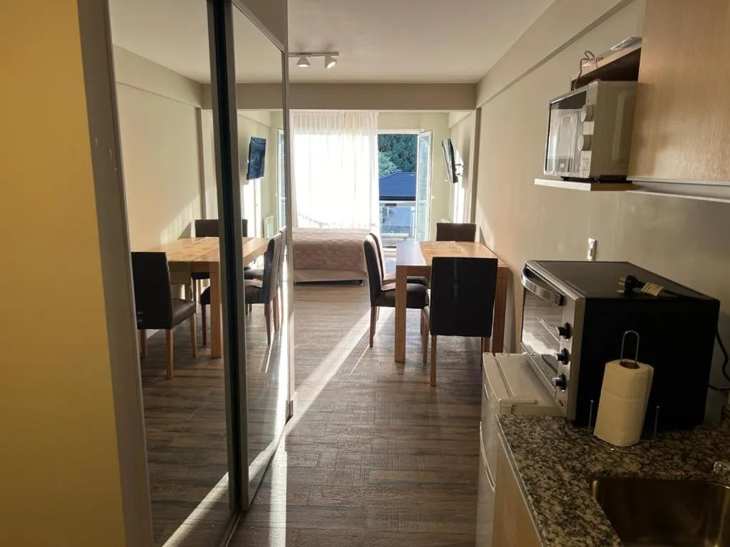 Mesa comedor y puerta del balcón del monoambiente de Güemes 540, con la cocina a la derecha