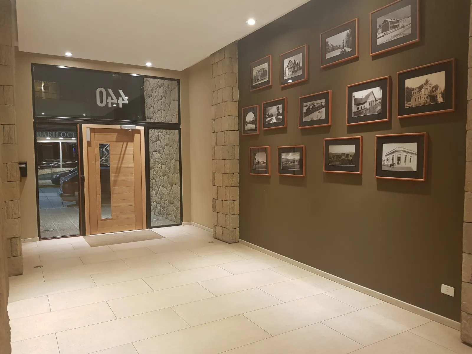 Ingreso del edificio de Av. San Martín 440 en Bariloche, con la pared de fotos históricas de la ciudad